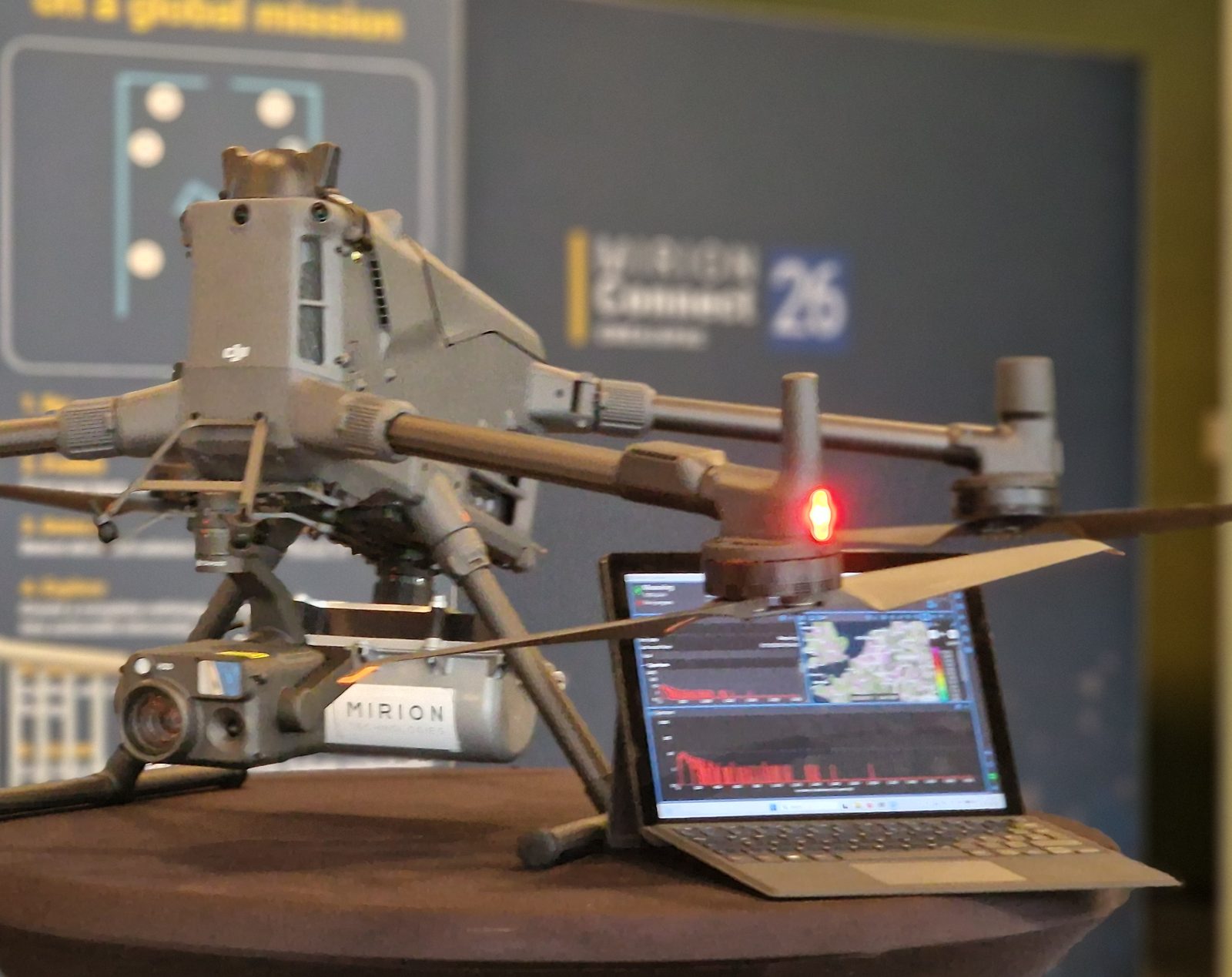 DJI M400 mit Mirion SPIR-Explorer und SKIDER, im Hintergrund Live-Daten auf einem Laptop